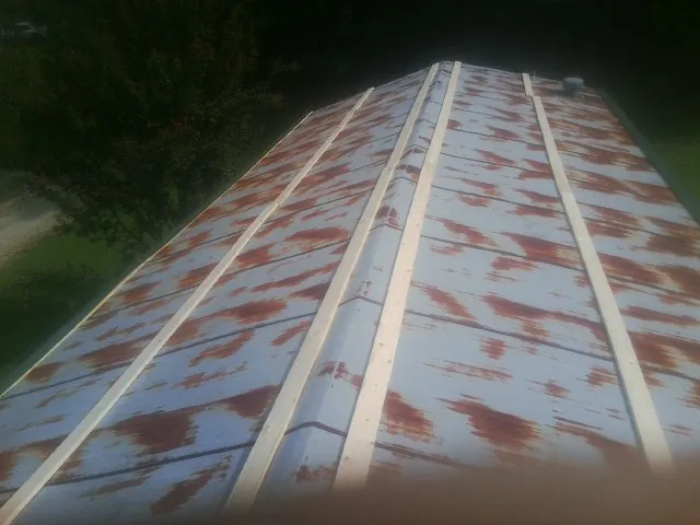 Rusted metal roof panels with new wood purlins before replacement — Storm Damage Roof Repair in Plattsburg by Roofing Brothers