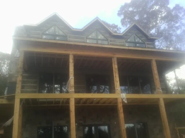 Dormers and porch framing on a large log home under construction — Roof Coating work by our crew in Plattsburg