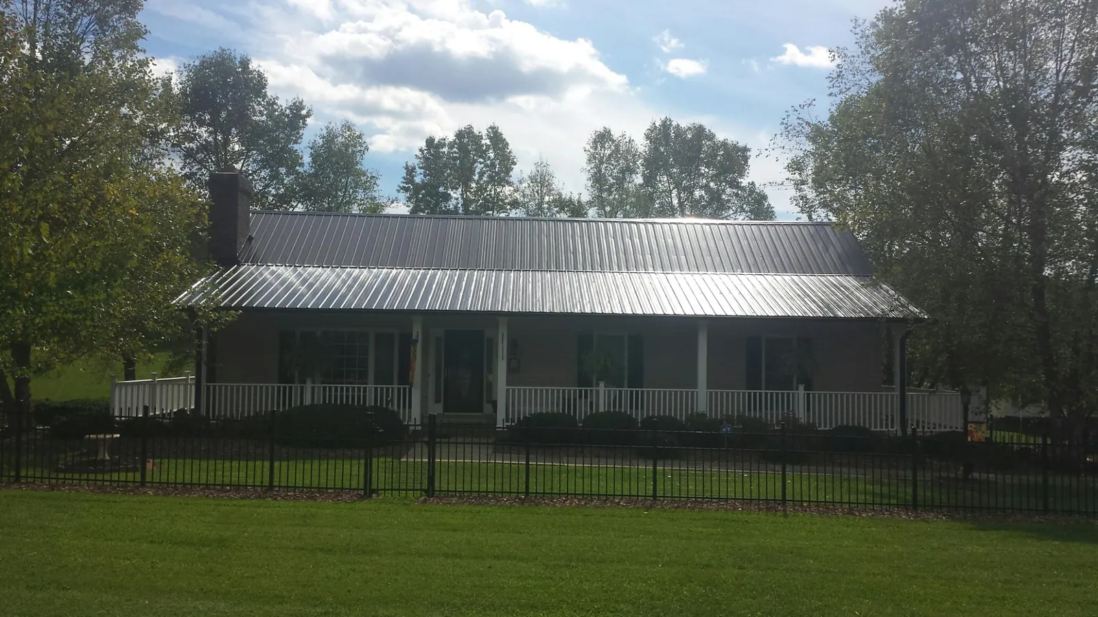Gray metal roof on a brick ranch with a full width front porch — Gutter Guard Installation work by our crew in Plattsburg