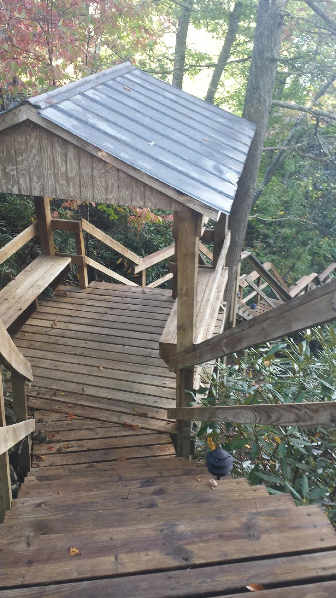 Metal roofed shelter over wooden steps on a wooded walkway — Skylight Repair & Installation work by our crew in Plattsburg