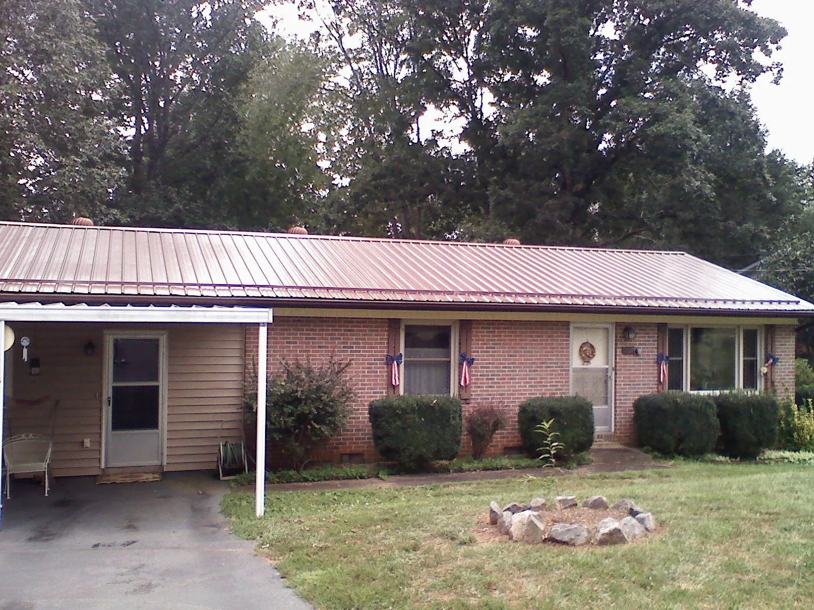 Bronze metal roof and carport on a brick ranch home — Roof Repair work by our crew in Plattsburg